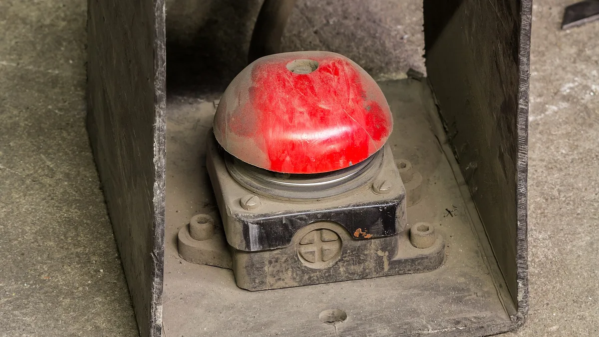A red industrial emergency stop button on a control panel
