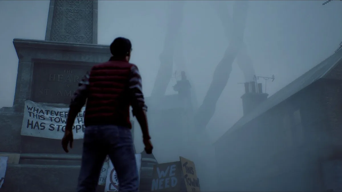 Figure in a striped red vest facing a stone town memorial in thick fog, protest placards propped against its base