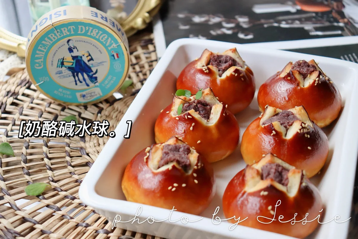 Six deep-brown lye-dipped buns snipped open and filled with red bean paste, arranged in a white baking dish