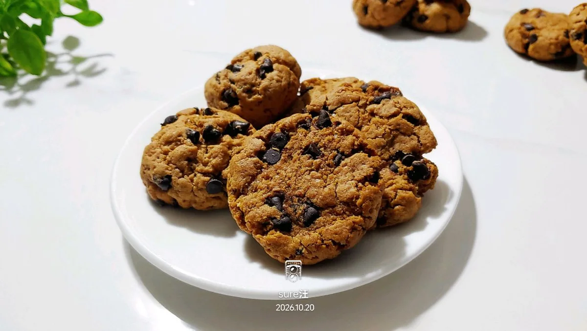 Golden brown sugar cookies with chocolate chips piled on a small white plate