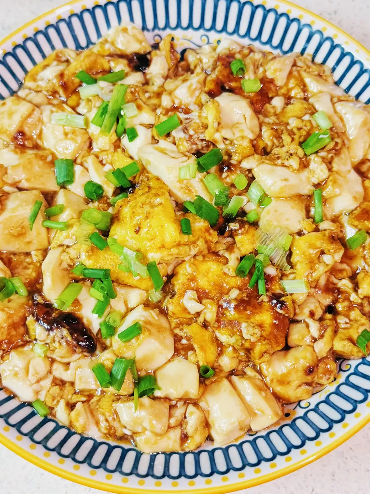 Silken tofu set under a golden egg layer, scattered with sliced scallion