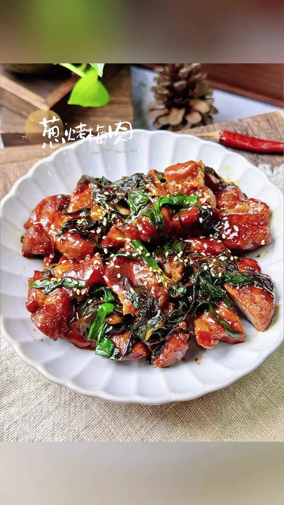 Slices of dark red braised pork collar over soft scallions on a white plate