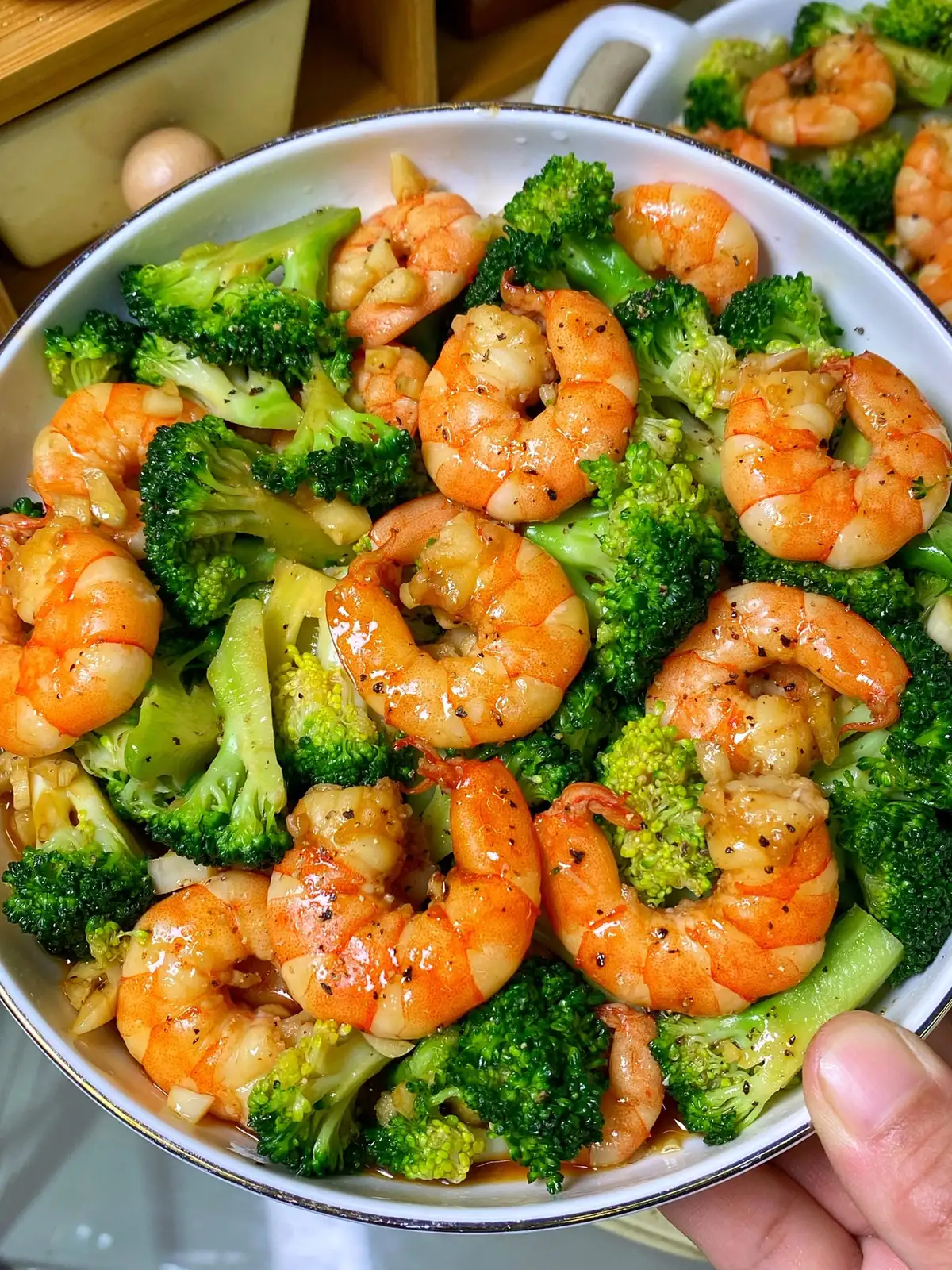 Pink shrimp and bright green broccoli florets tossed together in a pan