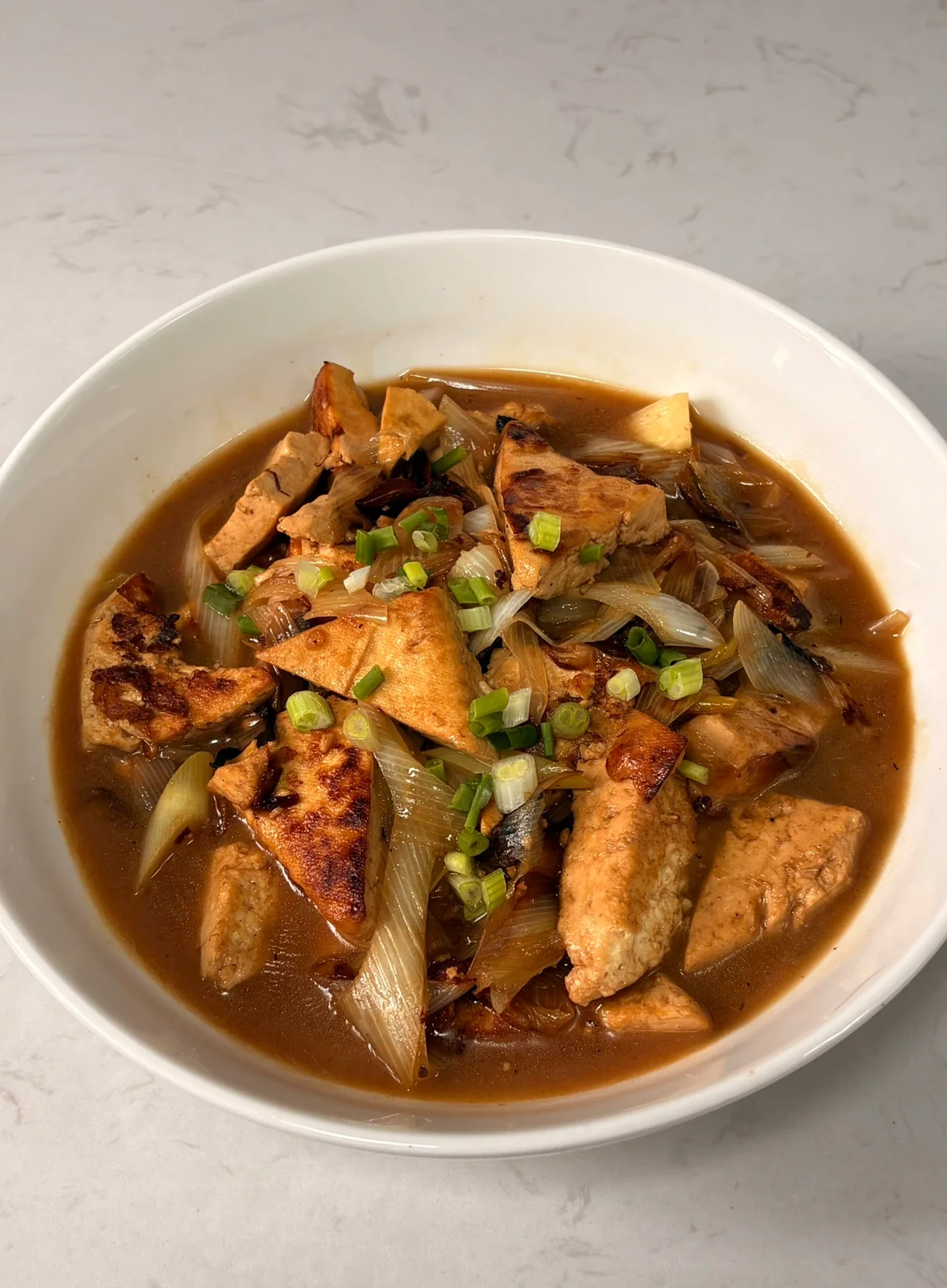Golden fried tofu triangles glazed in dark sauce with soft scallion whites