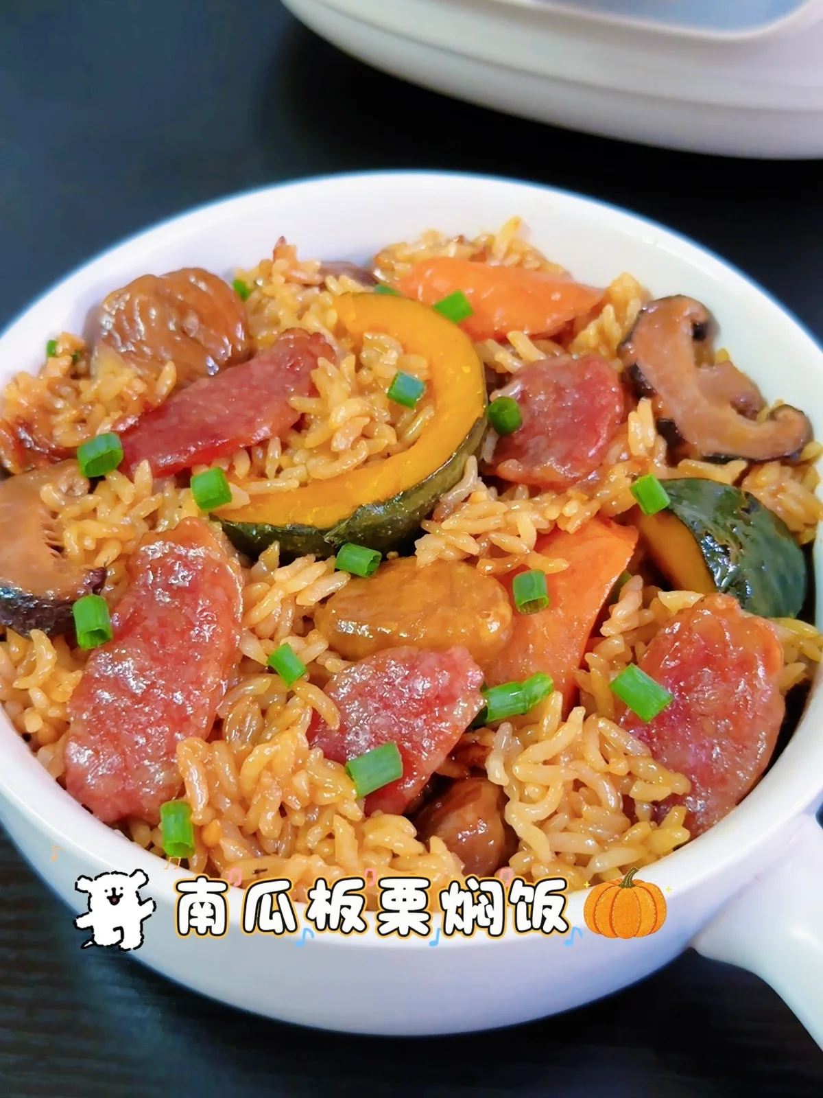 A white bowl of soy glazed rice with lap cheong slices, chestnuts, pumpkin and spring onion