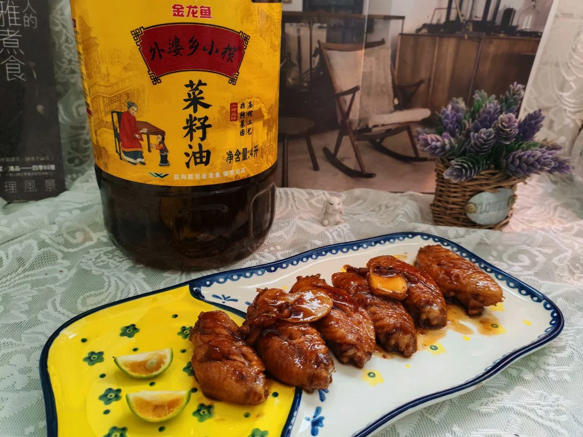 Glazed cola chicken wings on a blue and white plate with a cooking oil bottle behind