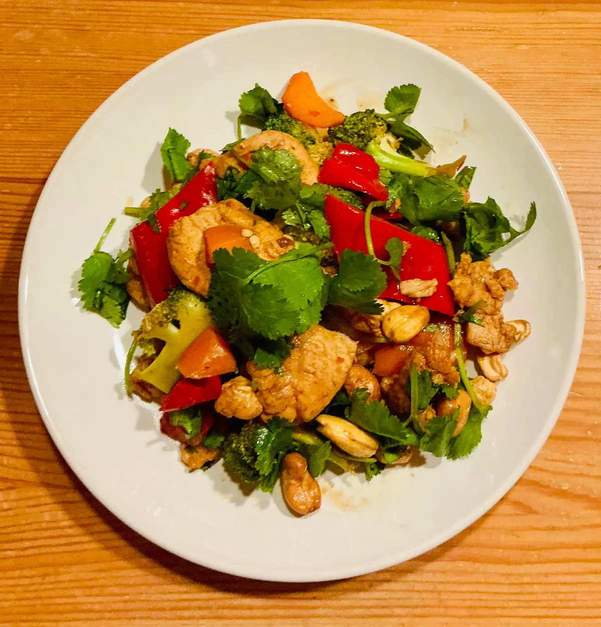 Stir-fried chicken pieces with broccoli florets, carrot slices, red pepper and roasted cashews coated in glossy sauce