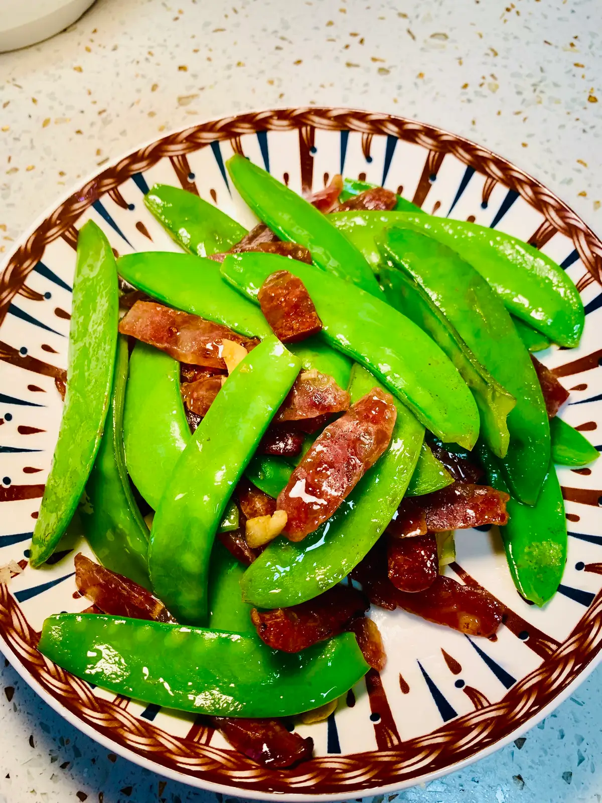 Bright green snow peas tossed with thin slices of cured Chinese sausage in a wok