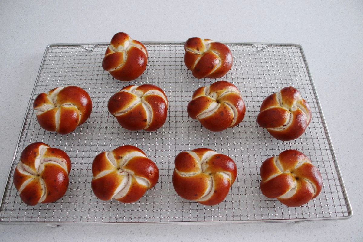 A tray of five-petal flower shaped lye buns with a deep reddish brown crust