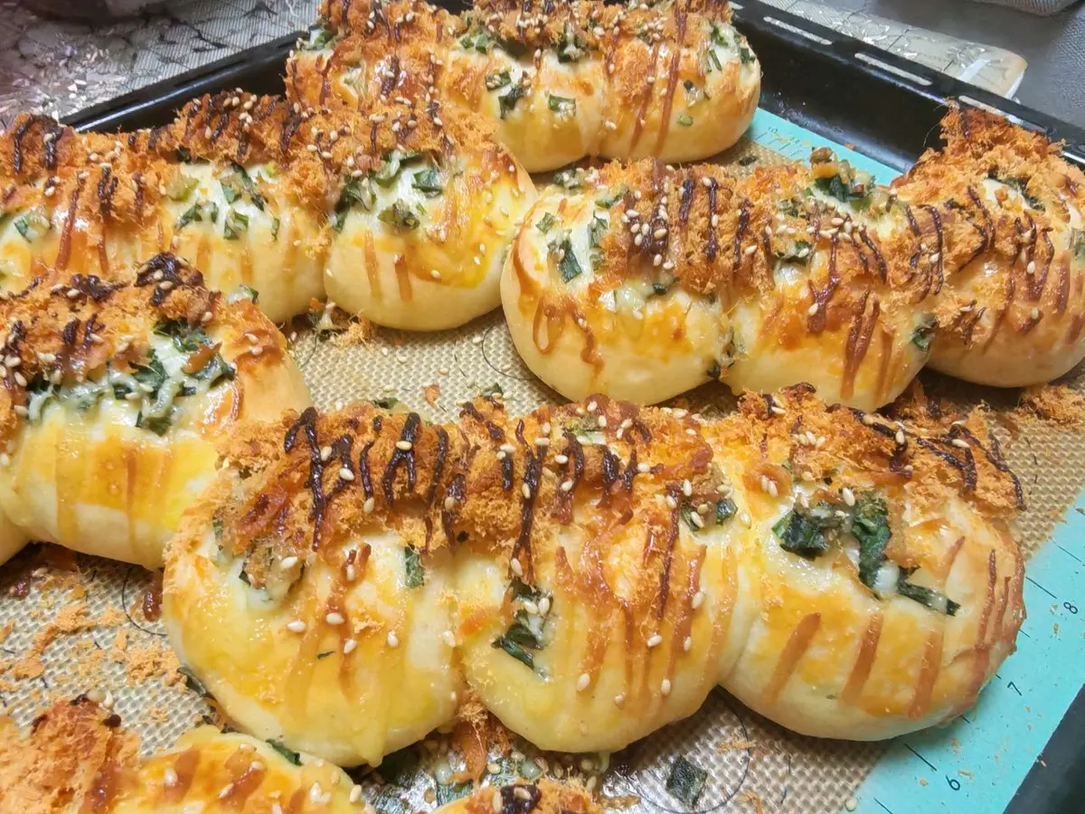 Golden topped buns scattered with scallions and pork floss on a baking tray