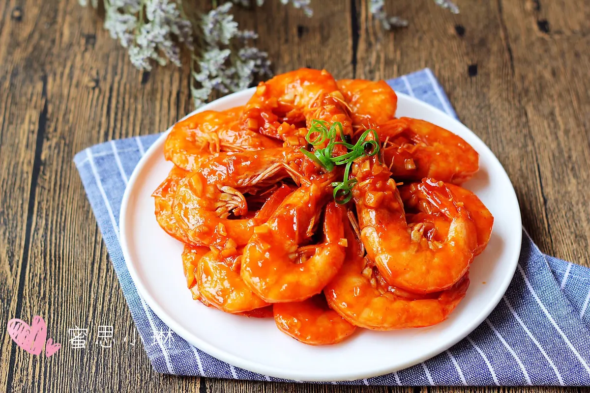 Bright red prawns coated in glossy ketchup sauce with minced garlic