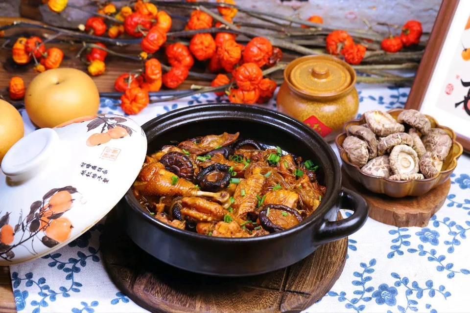 A black clay pot of braised chicken with dried shiitake caps and glass noodles