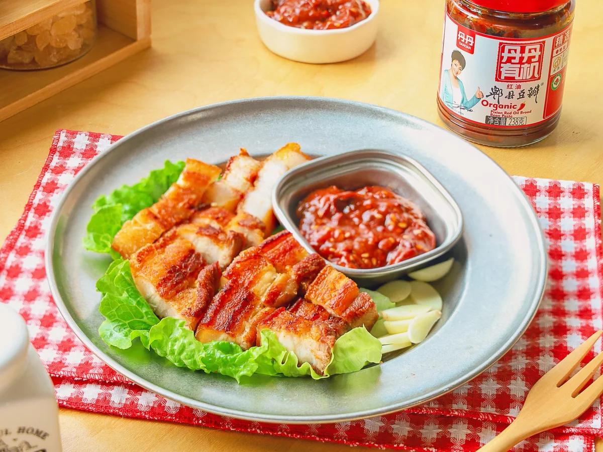 Sliced crisp pork belly with crackling skin on lettuce, with a red bean paste dip