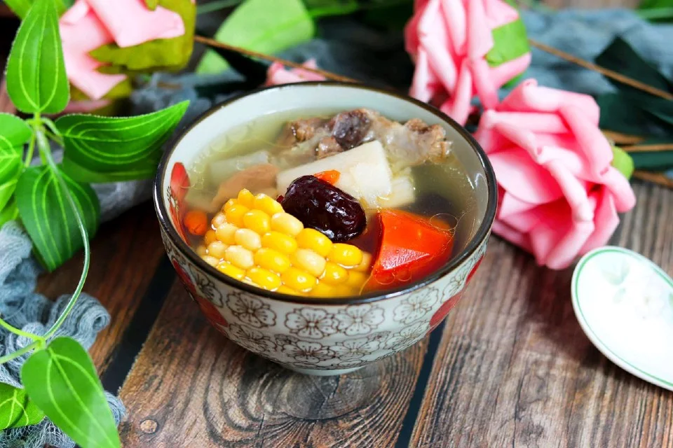 Clear pork rib soup with corn on the cob, yam, carrot and a red date in a patterned bowl